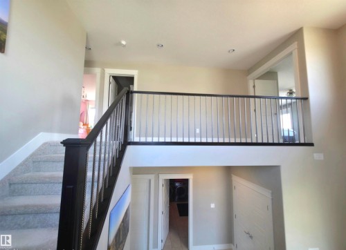 Carpeted staircase with dark wood newel post and railings featuring metal balusters - 1 Hemlock Close, Fort Saskatchewan, AB 