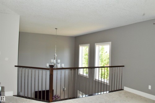 Upper-level landing featuring a chandelier, two windows, and carpeting - 1 Hemlock Close, Fort Saskatchewan, AB 