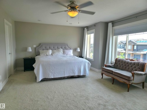 Expansive room featuring plush wall-to-wall carpeting, multiple windows with window treatments, and a ceiling fan with integrated lighting - 1 Hemlock Close, Fort Saskatchewan, AB 