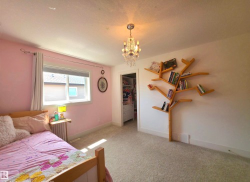 Bright room featuring a crystal chandelier, neutral carpeting, and a built-in tree-shaped bookshelf - 1 Hemlock Close, Fort Saskatchewan, AB 