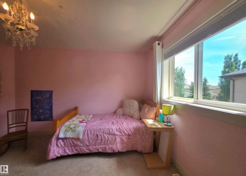 Room featuring a large window, a decorative chandelier, and light-colored carpet flooring - 1 Hemlock Close, Fort Saskatchewan, AB 