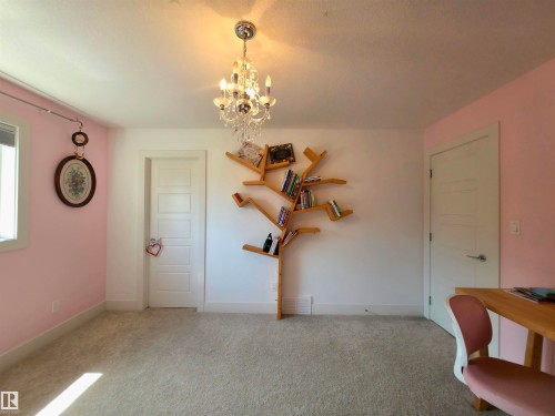 Bright room featuring light-colored carpeting, a crystal chandelier, and a decorative wall-mounted bookshelf - 1 Hemlock Close, Fort Saskatchewan, AB 