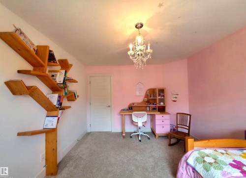 Plush carpeted flooring, a white paneled door, and a decorative crystal chandelier - 1 Hemlock Close, Fort Saskatchewan, AB 