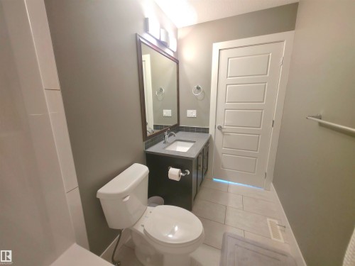Contemporary bathroom featuring a dark wood-finish vanity with a light-colored countertop, an undermount sink, and a framed mirror - 1 Hemlock Close, Fort Saskatchewan, AB 