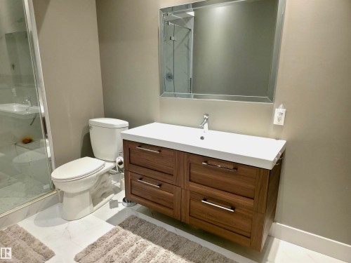 Modern bathroom featuring a wood-finish floating vanity with a white integrated sink, chrome faucet, and a large framed mirror - 1 Hemlock Close, Fort Saskatchewan, AB 