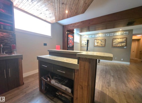 Wet bar with concrete countertops, wood-finish cabinetry, and a mosaic tile backsplash - 1 Hemlock Close, Fort Saskatchewan, AB 