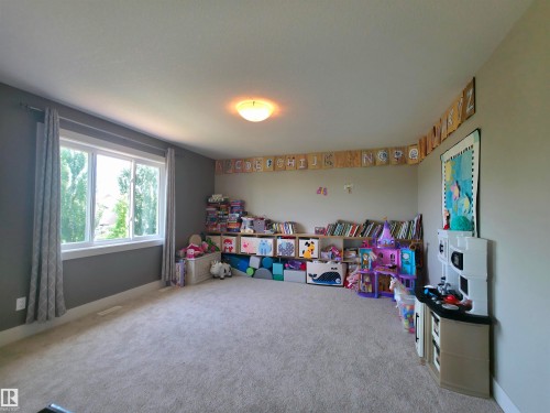 Carpeted room featuring a large window, light gray walls, and white trim - 1 Hemlock Close, Fort Saskatchewan, AB 