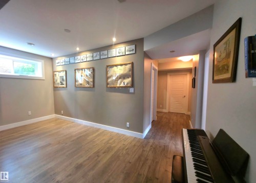 Spacious room featuring wood-finish flooring, recessed lighting, and a window with white trim - 1 Hemlock Close, Fort Saskatchewan, AB 