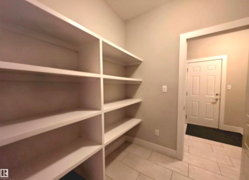 Built-in shelving providing ample storage, neutral wall paint, white trim, and light-toned tile flooring - 1 Hemlock Close, Fort Saskatchewan, AB 