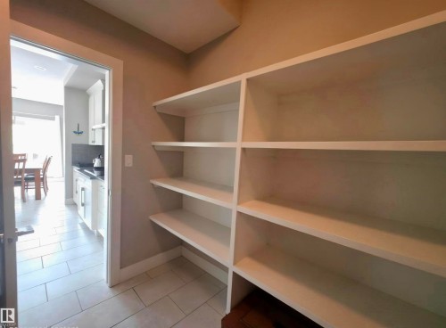 Pantry featuring extensive built-in shelving, tile flooring, and direct access to the kitchen - 1 Hemlock Close, Fort Saskatchewan, AB 