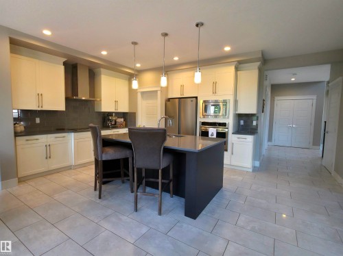 Contemporary kitchen featuring a central island with pendant lighting, light-toned cabinetry, stainless steel appliances, and tile flooring - 1 Hemlock Close, Fort Saskatchewan, AB 
