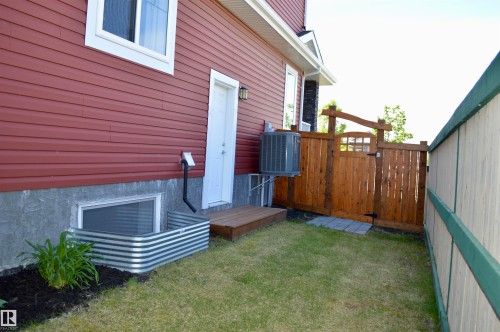 Red siding exterior with white window trim and a wood plank door - 1 Hemlock Close, Fort Saskatchewan, AB 