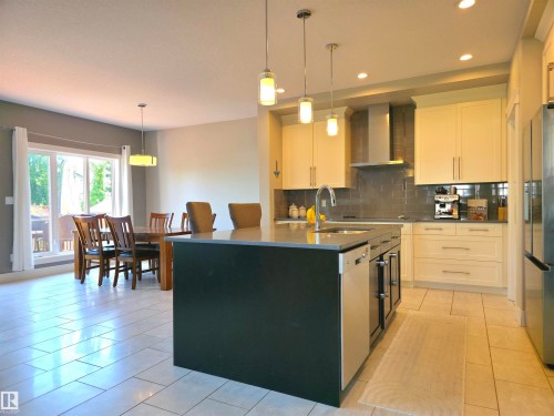 Contemporary kitchen featuring a central island with integrated sink, stainless steel appliances, light cabinetry, and tiled backsplash - 1 Hemlock Close, Fort Saskatchewan, AB 