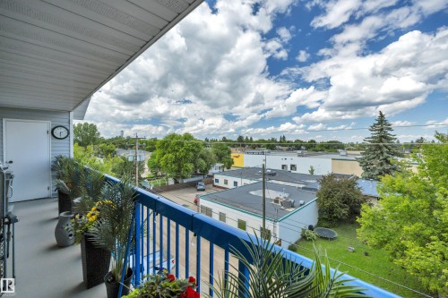 Outdoor balcony with blue metal railing, gray siding, and a solid white door - 305 5212 48 Avenue, Wetaskiwin, AB 