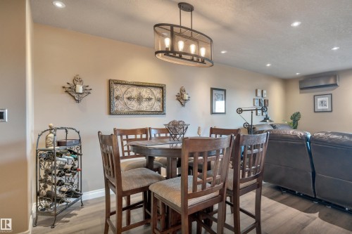 Open-concept entertaining space featuring recessed lighting, a contemporary chandelier, and wood-finish flooring - 305 5212 48 Avenue, Wetaskiwin, AB 