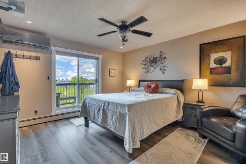 Bedroom featuring wood-finish flooring, a ceiling fan, and a built-in split-system air conditioning unit - 305 5212 48 Avenue, Wetaskiwin, AB 