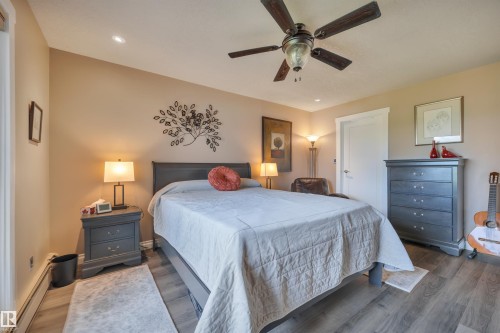 Interior space featuring wood-finish flooring, a ceiling fan with integrated lighting, recessed lighting, and a white interior door with a lever handle - 305 5212 48 Avenue, Wetaskiwin, AB 