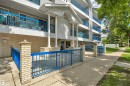 Multi-story building exterior featuring light-colored siding and a brick-finish foundation - 305 5212 48 Avenue, Wetaskiwin, AB 