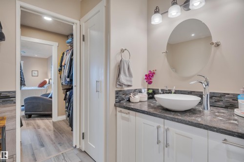 Bathroom vanity featuring a vessel sink, single-handle chrome faucet, oval mirror, and three-light vanity bar - 305 5212 48 Avenue, Wetaskiwin, AB 