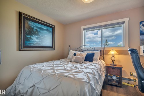 Bedroom featuring a large window, wood-finish flooring, and neutral wall tones - 305 5212 48 Avenue, Wetaskiwin, AB 