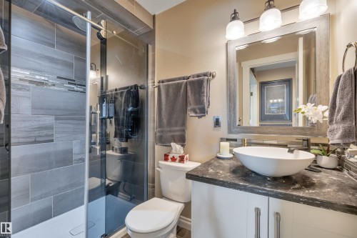 Bathroom featuring a glass-enclosed shower with large format grey tile and a decorative tile accent band - 305 5212 48 Avenue, Wetaskiwin, AB 