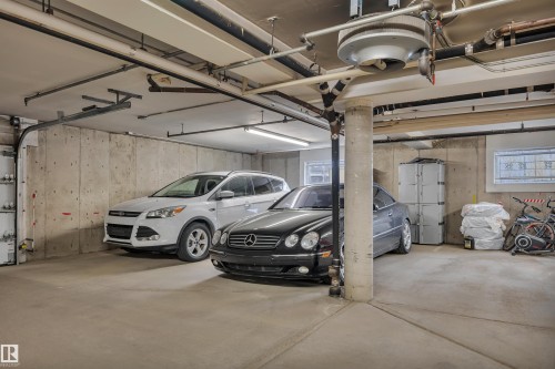 Spacious concrete garage featuring a durable concrete floor, exposed concrete walls, and overhead fluorescent lighting - 305 5212 48 Avenue, Wetaskiwin, AB 