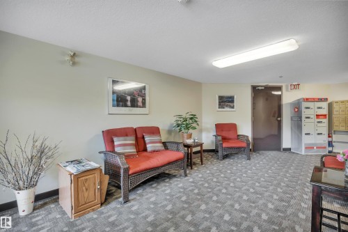 Lobby area featuring patterned carpeting, recessed lighting, and a dark wood-finish entry door - 305 5212 48 Avenue, Wetaskiwin, AB 
