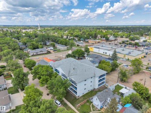 Multi-story residential building with light-colored siding and a grey shingle roof - 305 5212 48 Avenue, Wetaskiwin, AB 