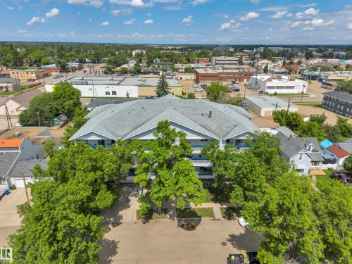 Multi-unit building featuring a multi-pitched roof with asphalt shingles, light blue siding, and individual balconies - 305 5212 48 Avenue, Wetaskiwin, AB 