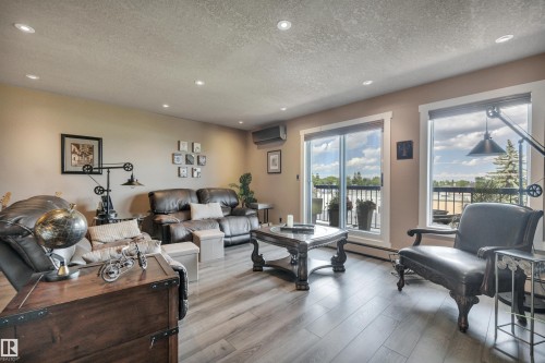 Spacious living area featuring wood-finish flooring, recessed lighting, and soft neutral wall tones - 305 5212 48 Avenue, Wetaskiwin, AB 