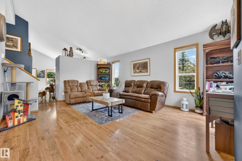 Inviting living space featuring wood-finish flooring, vaulted ceilings, and ample natural light from multiple windows - 1 Primrose Boulevard, Sherwood Park, AB 