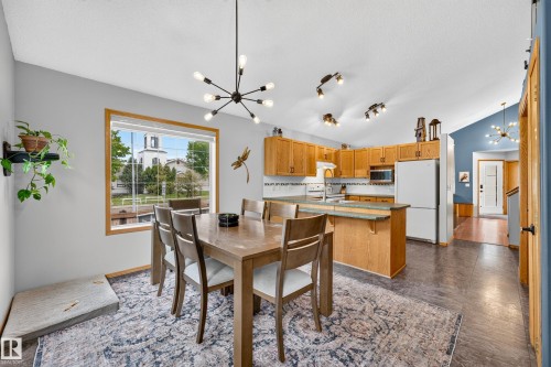Open-concept kitchen and dining area featuring light wood cabinetry, white appliances, and a central island with a countertop - 1 Primrose Boulevard, Sherwood Park, AB 