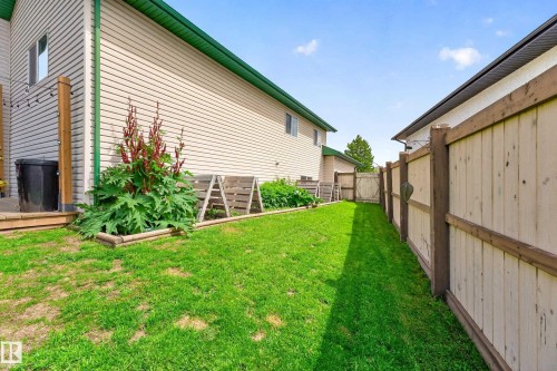 Expansive green space featuring a wooden privacy fence, raised garden beds, and a wood deck - 1 Primrose Boulevard, Sherwood Park, AB 