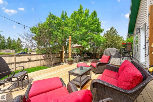 Expansive wood deck with string lighting, bordered by a wooden privacy fence and mature trees - 1 Primrose Boulevard, Sherwood Park, AB 