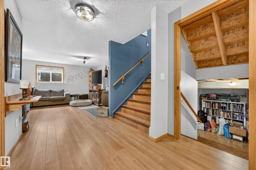 Lower level living area with wood-finish flooring, recessed lighting, and a painted blue stairwell featuring a wood handrail - 1 Primrose Boulevard, Sherwood Park, AB 