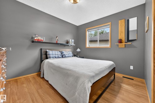 Bedroom featuring neutral gray walls, wood-finish flooring, and a single window with wood trim - 1 Primrose Boulevard, Sherwood Park, AB 
