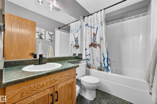 Bathroom vanity with wood-finish cabinetry, a green countertop, and an oval undermount sink featuring a matte black faucet - 1 Primrose Boulevard, Sherwood Park, AB 