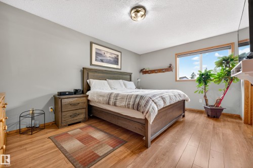 Bedroom featuring wood-finish flooring, a large window, a ceiling-mounted light fixture, and light gray painted walls - 1 Primrose Boulevard, Sherwood Park, AB 