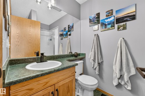 Bathroom featuring a vanity with wood-finish cabinetry, a dark green speckled countertop, and a white undermount sink with a matte black faucet - 1 Primrose Boulevard, Sherwood Park, AB 