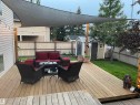 Expansive wood deck with a partial shade sail, string lighting, and direct access to a manicured lawn - 1 Primrose Boulevard, Sherwood Park, AB 