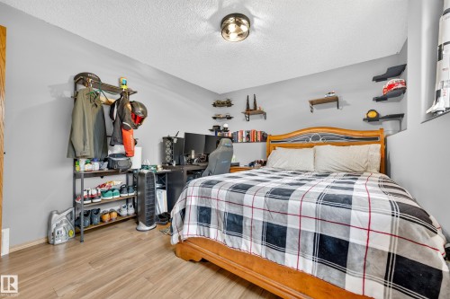 Bedroom featuring wood-finish flooring, light gray walls, a ceiling-mounted light fixture, and built-in wall shelving - 1 Primrose Boulevard, Sherwood Park, AB 