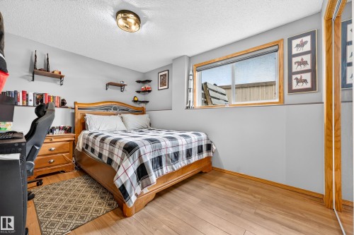 Bedroom featuring wood-finish flooring, light gray walls, built-in shelving, a large window with wood trim, and a ceiling-mounted light fixture - 1 Primrose Boulevard, Sherwood Park, AB 