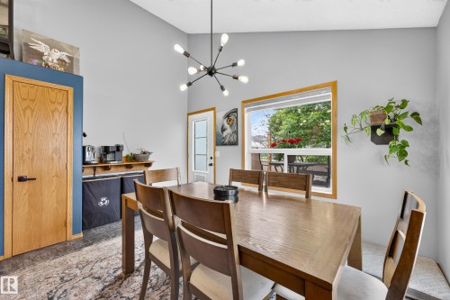 Vaulted ceiling featuring a modern chandelier, natural wood trim window, and a door with frosted glass paneling - 1 Primrose Boulevard, Sherwood Park, AB 