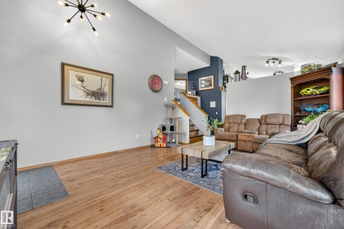 Vaulted ceiling with a contemporary sputnik chandelier, wood-finish flooring, and a staircase with a wood handrail - 1 Primrose Boulevard, Sherwood Park, AB 