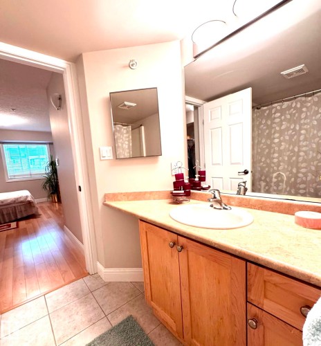 Ensuite featuring a light wood-finish vanity with a built-in sink, mirror, and overhead lighting - 330 13111 140 Avenue, Edmonton, AB 