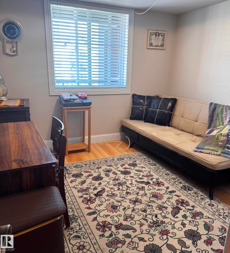 Warmly appointed room featuring wood-finish flooring and a central window with horizontal blinds - 330 13111 140 Avenue, Edmonton, AB 