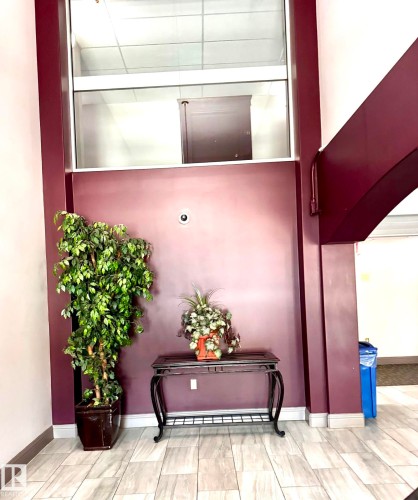 Tiled entry space featuring light-toned plank flooring, a rich burgundy accent wall, and an overhead glass panel - 330 13111 140 Avenue, Edmonton, AB 
