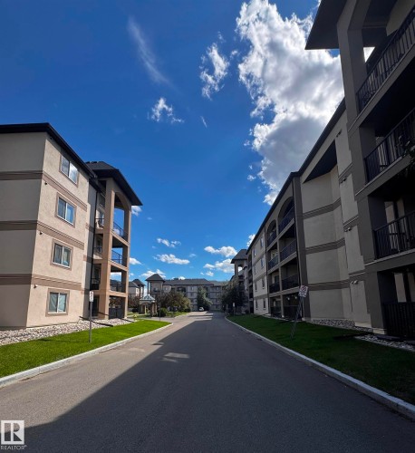 Paved thoroughfare flanked by multi-story residential buildings featuring balconies and manicured lawns - 330 13111 140 Avenue, Edmonton, AB 
