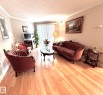 Living area featuring light wood-finish flooring, crown molding, and a sliding glass door with vertical blinds - 330 13111 140 Avenue, Edmonton, AB 