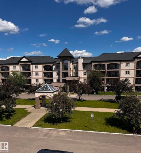 Multistory building exterior featuring a central turret, multiple balconies, a covered entry, and pitched roofs - 330 13111 140 Avenue, Edmonton, AB 